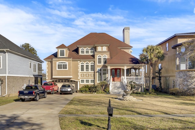 view of front of house featuring a front yard, driveway, an attached garage, a chimney, and french doors