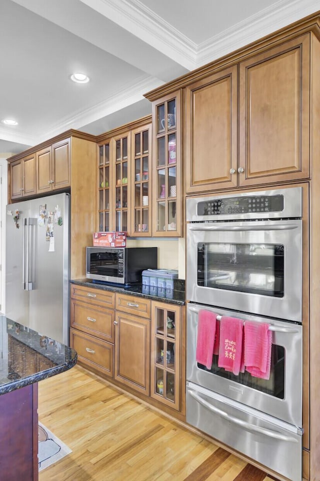 kitchen with light wood finished floors, brown cabinetry, appliances with stainless steel finishes, and crown molding