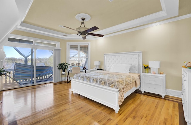 bedroom featuring access to exterior, light wood-style flooring, crown molding, and a tray ceiling