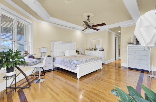 bedroom with light wood-style flooring, crown molding, a raised ceiling, and baseboards