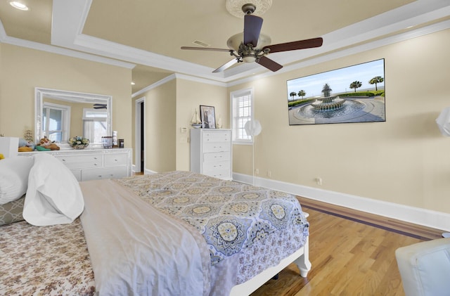 bedroom with a raised ceiling, a ceiling fan, wood finished floors, crown molding, and baseboards