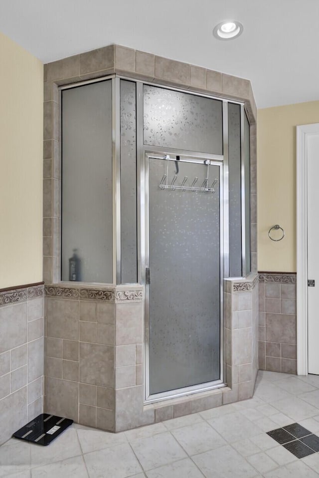 bathroom with tile walls, wainscoting, and a shower stall