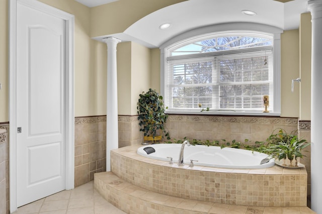 full bathroom with tile patterned flooring, a garden tub, tile walls, and ornate columns