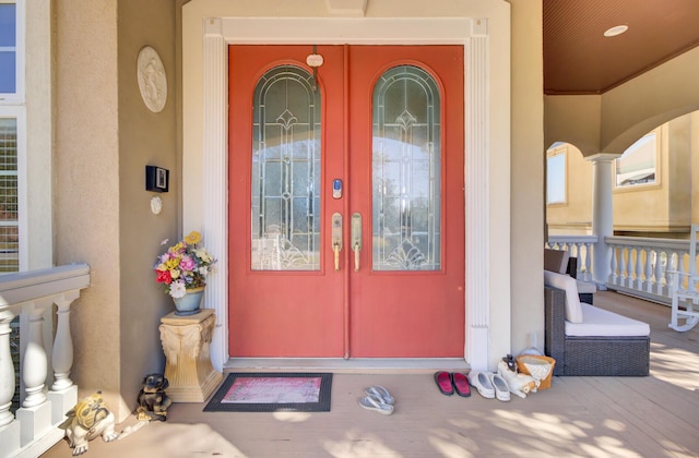 entrance to property featuring french doors, covered porch, and stucco siding