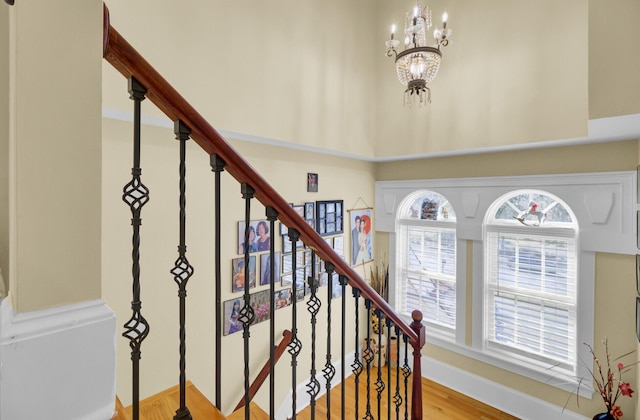 stairway with a chandelier, baseboards, and wood finished floors