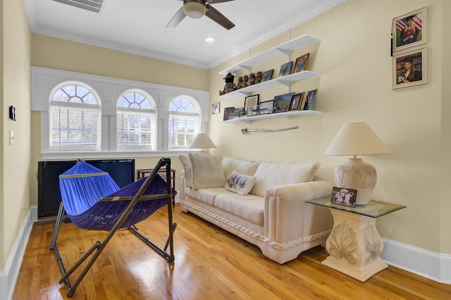 living area featuring plenty of natural light, wood finished floors, a ceiling fan, and ornamental molding