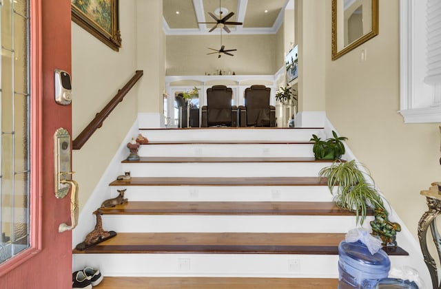 staircase with ornamental molding, a towering ceiling, and ceiling fan