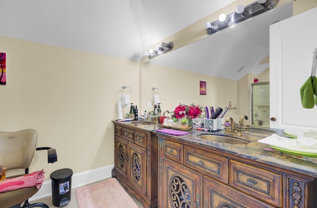 bathroom with a sink, baseboards, double vanity, and vaulted ceiling