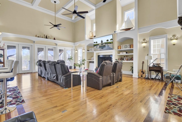 living area with light wood finished floors, coffered ceiling, a fireplace, and a ceiling fan