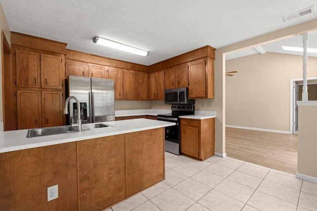 8116 Long Shadow Ln, North Charleston, SC 29406 - kitchen with appliances with stainless steel finishes, brown cabinetry, light countertops, a peninsula, and light tile patterned flooring