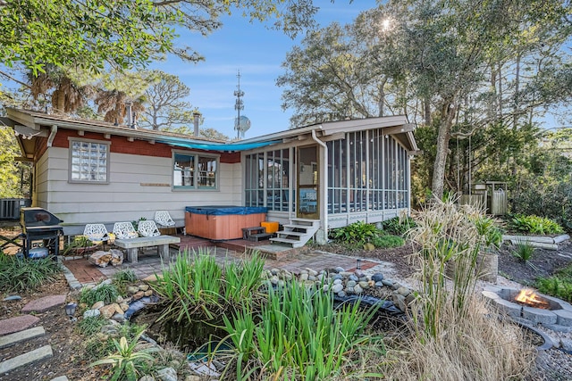 520 E Huron Ave, Folly Beach, SC 29439 - rear view of house with a hot tub, an outdoor fire pit, a patio, and a sunroom