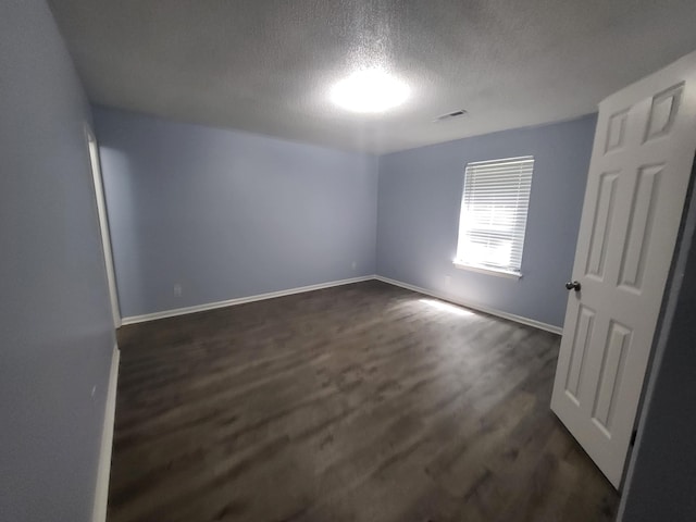 empty room featuring dark hardwood / wood-style flooring and a textured ceiling