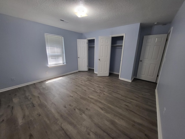 unfurnished bedroom with dark hardwood / wood-style flooring and a textured ceiling