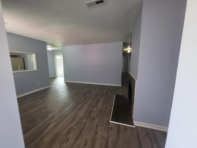 unfurnished living room featuring dark hardwood / wood-style flooring and a textured ceiling