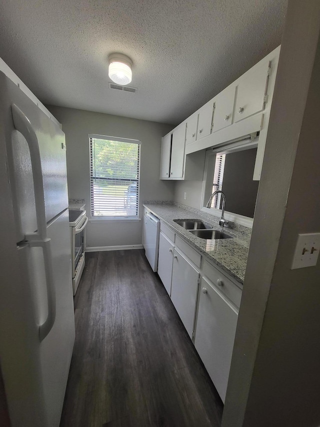 kitchen with light stone counters, white appliances, sink, dark hardwood / wood-style floors, and white cabinetry