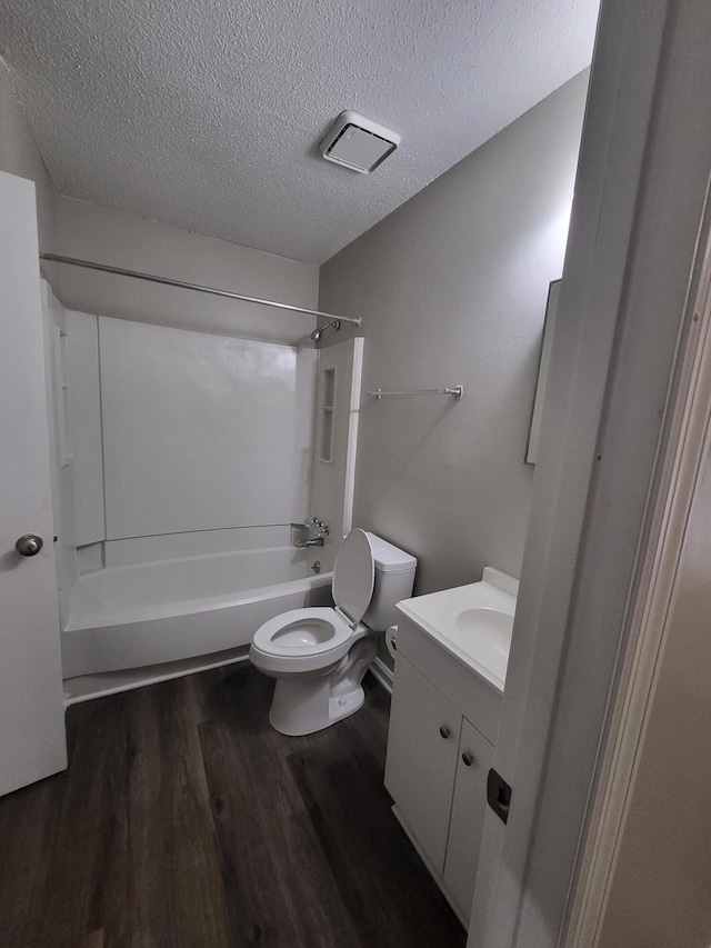 full bathroom with hardwood / wood-style floors, vanity, shower / tub combination, toilet, and a textured ceiling