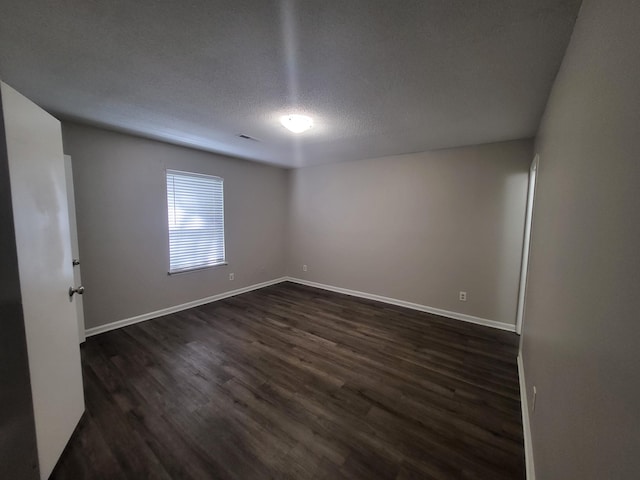 unfurnished room with a textured ceiling and dark hardwood / wood-style floors