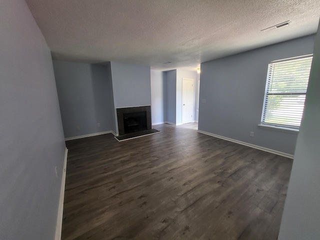 unfurnished living room with a textured ceiling and dark wood-type flooring