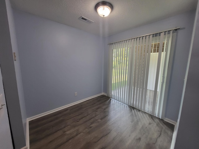 empty room featuring dark hardwood / wood-style floors and a textured ceiling