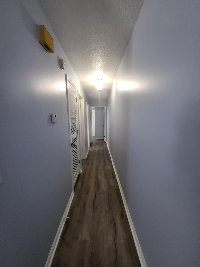 hall with a textured ceiling and dark hardwood / wood-style flooring