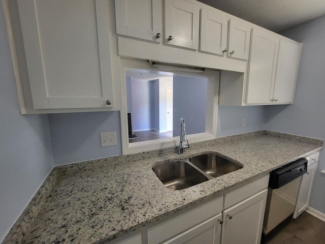 kitchen with light stone countertops, white cabinetry, sink, and stainless steel dishwasher