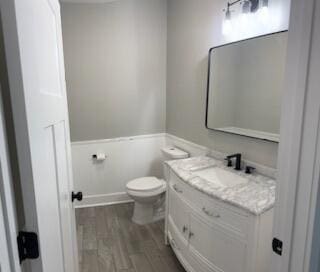 bathroom with wood-type flooring, vanity, and toilet