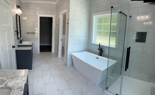 bathroom featuring vanity, shower with separate bathtub, and tile walls