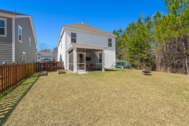 back of house featuring a lawn, a fire pit, a fenced backyard, and a sunroom