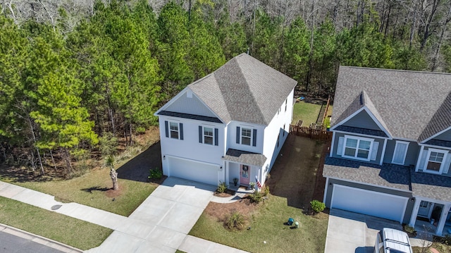 view of front of property featuring stucco siding, a shingled roof, concrete driveway, a front lawn, and a garage