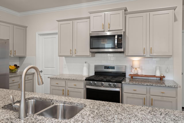 kitchen featuring ornamental molding, a sink, appliances with stainless steel finishes, decorative backsplash, and light stone countertops