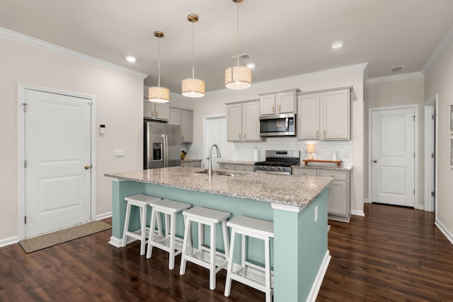 kitchen featuring a kitchen bar, dark wood-type flooring, a sink, tasteful backsplash, and stainless steel appliances