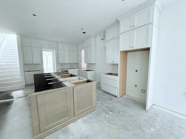 kitchen with washer / clothes dryer, a center island, and white cabinets