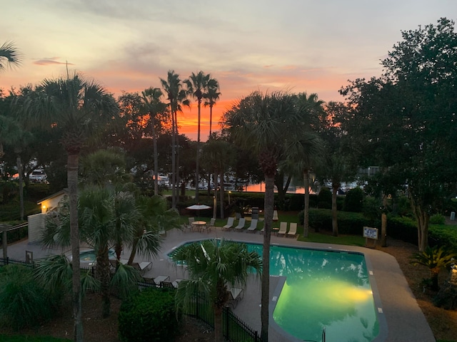 pool at dusk featuring a patio area