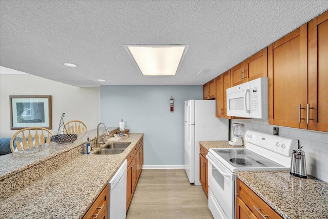 kitchen with a kitchen bar, backsplash, white appliances, light wood-type flooring, and sink