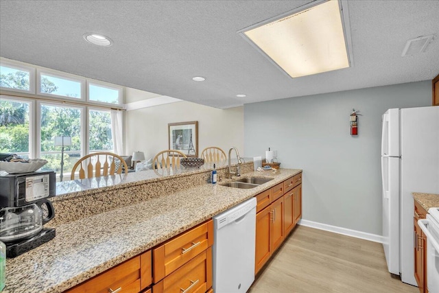 kitchen with light hardwood / wood-style floors, sink, white appliances, a textured ceiling, and light stone counters