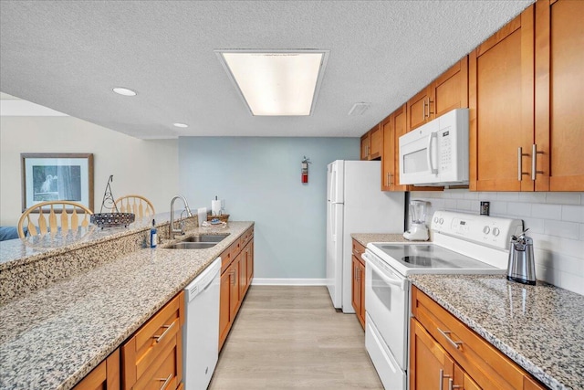 kitchen with light hardwood / wood-style floors, decorative backsplash, white appliances, light stone countertops, and sink