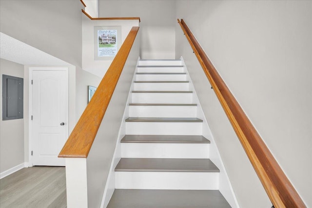 staircase featuring hardwood / wood-style flooring and electric panel