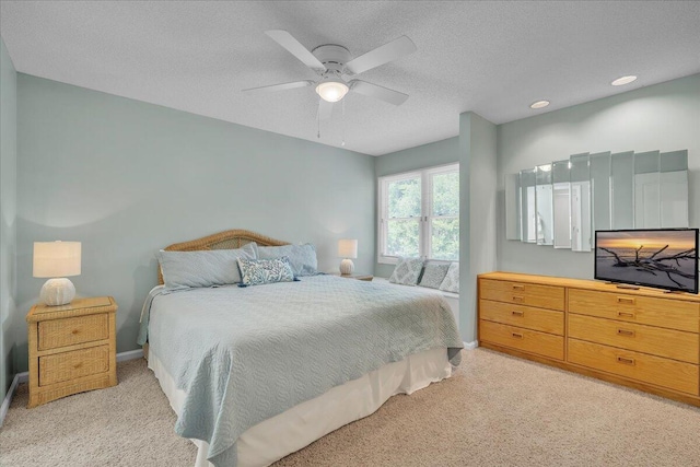 bedroom featuring ceiling fan, light carpet, and a textured ceiling