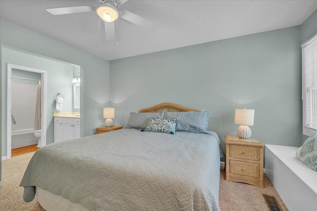 bedroom featuring ceiling fan, a textured ceiling, and ensuite bathroom