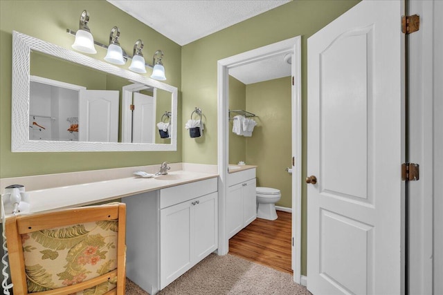 bathroom with a textured ceiling, toilet, and vanity