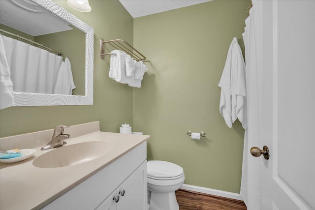 bathroom with toilet, vanity, a textured ceiling, and hardwood / wood-style flooring