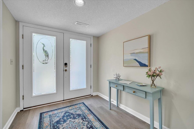 foyer entrance featuring a textured ceiling, hardwood / wood-style flooring, and french doors