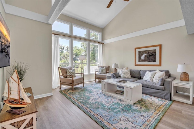 living room featuring light hardwood / wood-style floors, high vaulted ceiling, and ceiling fan