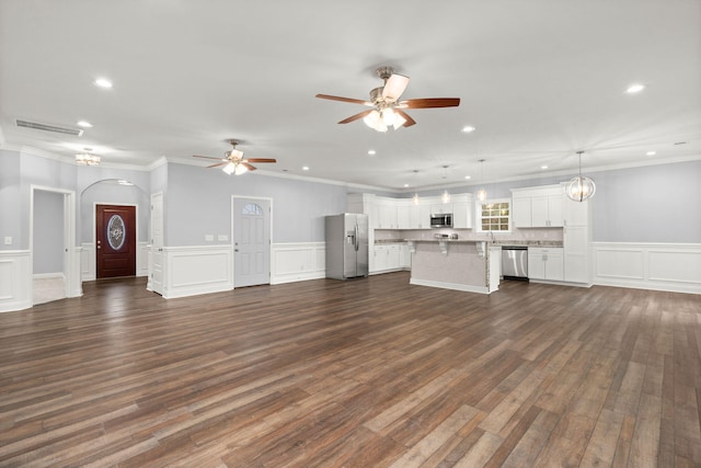 unfurnished living room with visible vents, arched walkways, dark wood-type flooring, crown molding, and recessed lighting