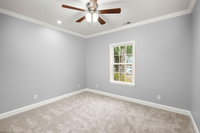 carpeted spare room featuring ornamental molding, visible vents, baseboards, and a ceiling fan