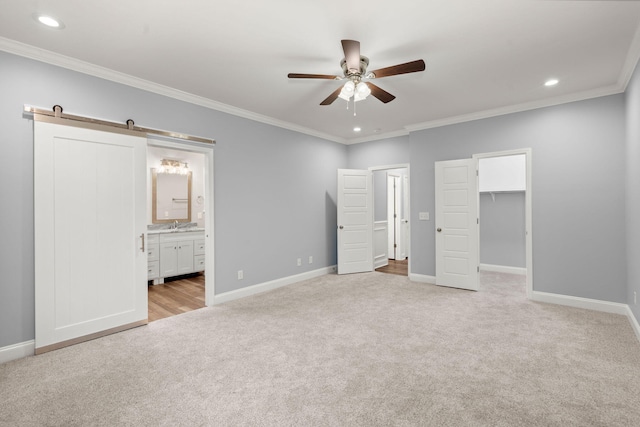 unfurnished bedroom with ornamental molding, a barn door, and light colored carpet