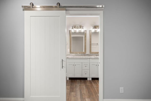 bathroom with double vanity, wood finished floors, and a sink