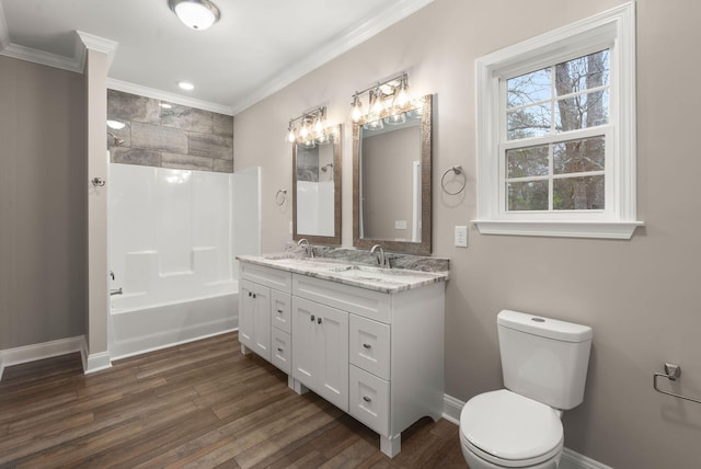 bathroom with crown molding, toilet, a sink, wood finished floors, and baseboards