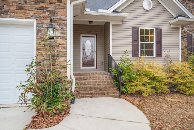 entrance to property with a garage and stone siding