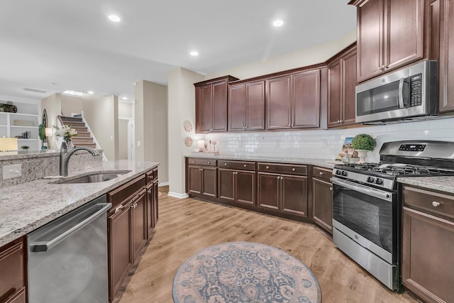 9829 English Elm St, Ladson, SC 29456 - kitchen featuring appliances with stainless steel finishes, a sink, light stone counters, decorative backsplash, and light wood-style flooring